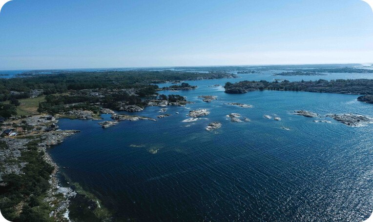 Large lake area photographed from above. It is very lightly built-up, interspersed with forests and above all there is a lot of water, interrupted only by the occasional stone emerging from the water.