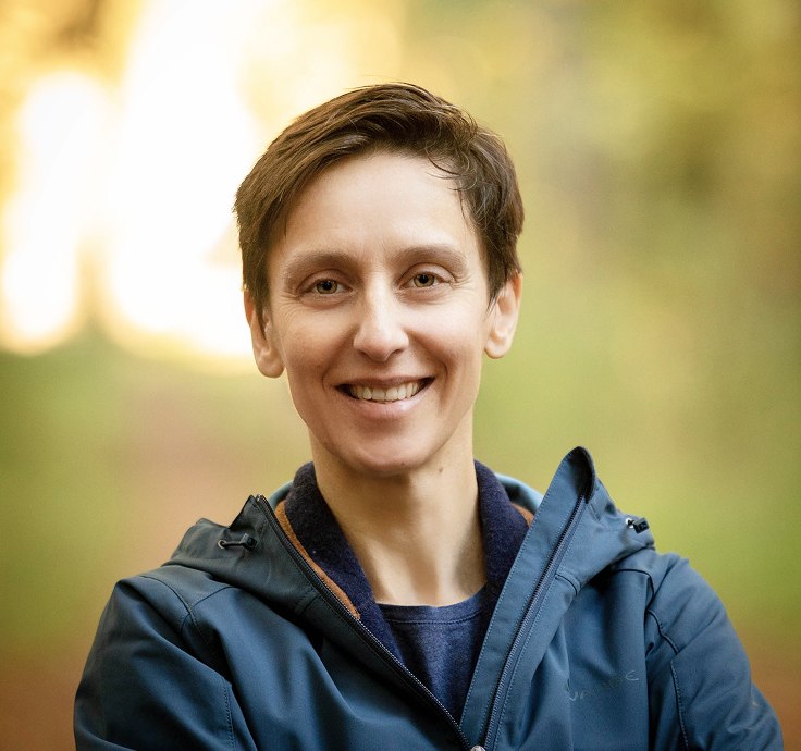 White woman with short brown hair and brown eyes smiles friendly into the camera.