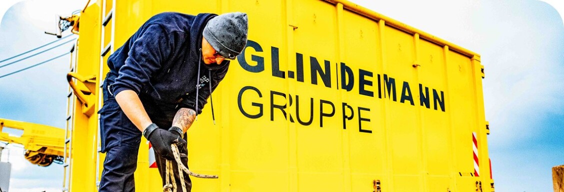 A large yellow container labelled GL.INDEMANN GRUPPE. A person dressed in blue is standing in front of it, handling nets.
