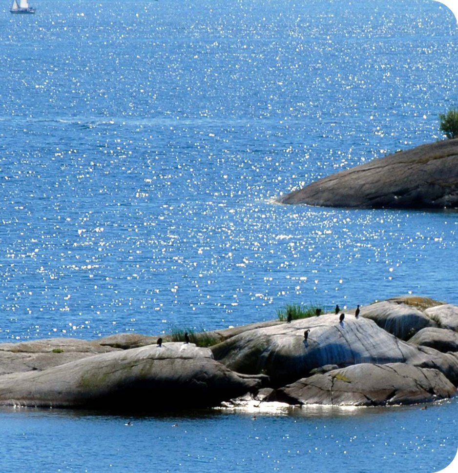 Small, rocky islands with hardly any vegetation stretch out of the dark blue water, which glistens in the sun.